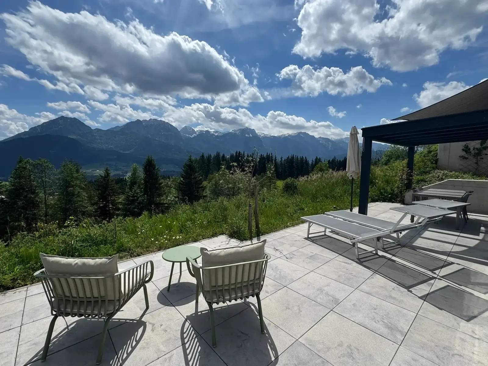 Südterrasse mit Gartenmöbeln und Liegen, dahinter das Tennengebirge